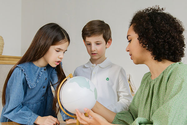 two children and a teacher viewing a globe