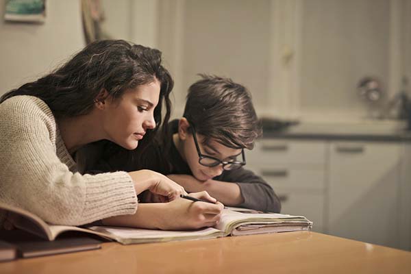 woman helping a young boy complete a workbook