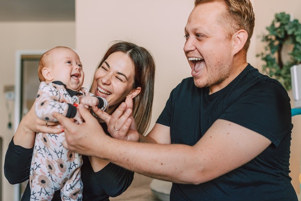 smiling mother and father playing with a baby